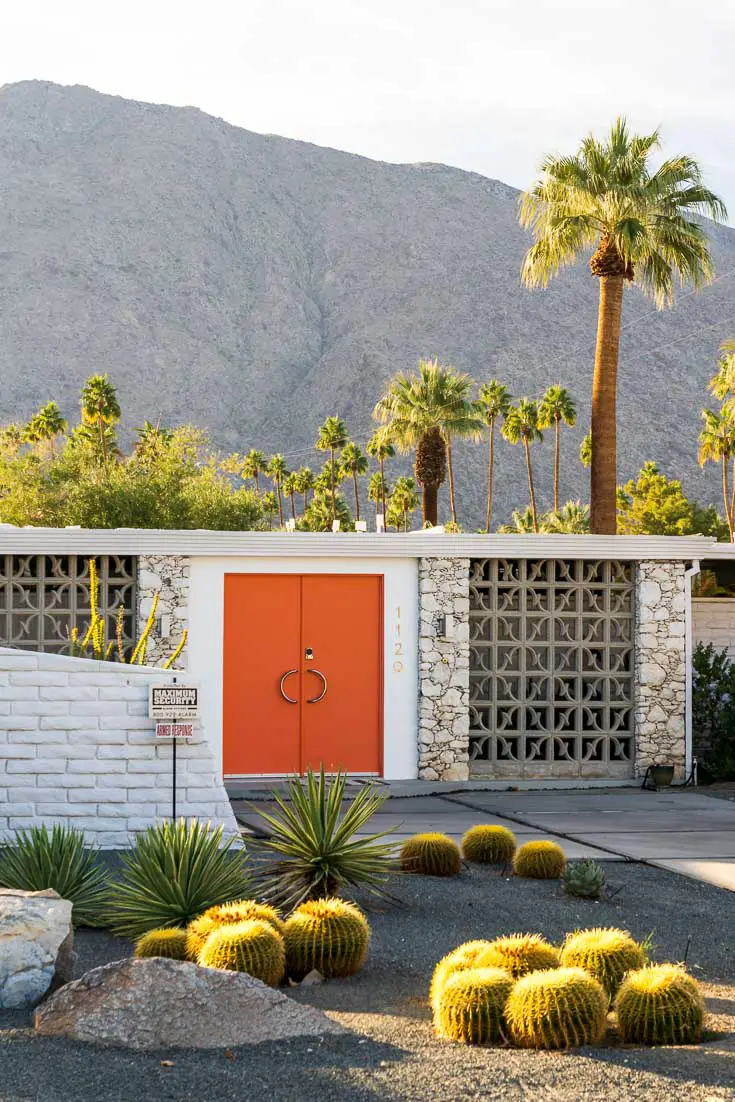Mid-Century home with breeze bricks and orange front door, with palms and mountain in background