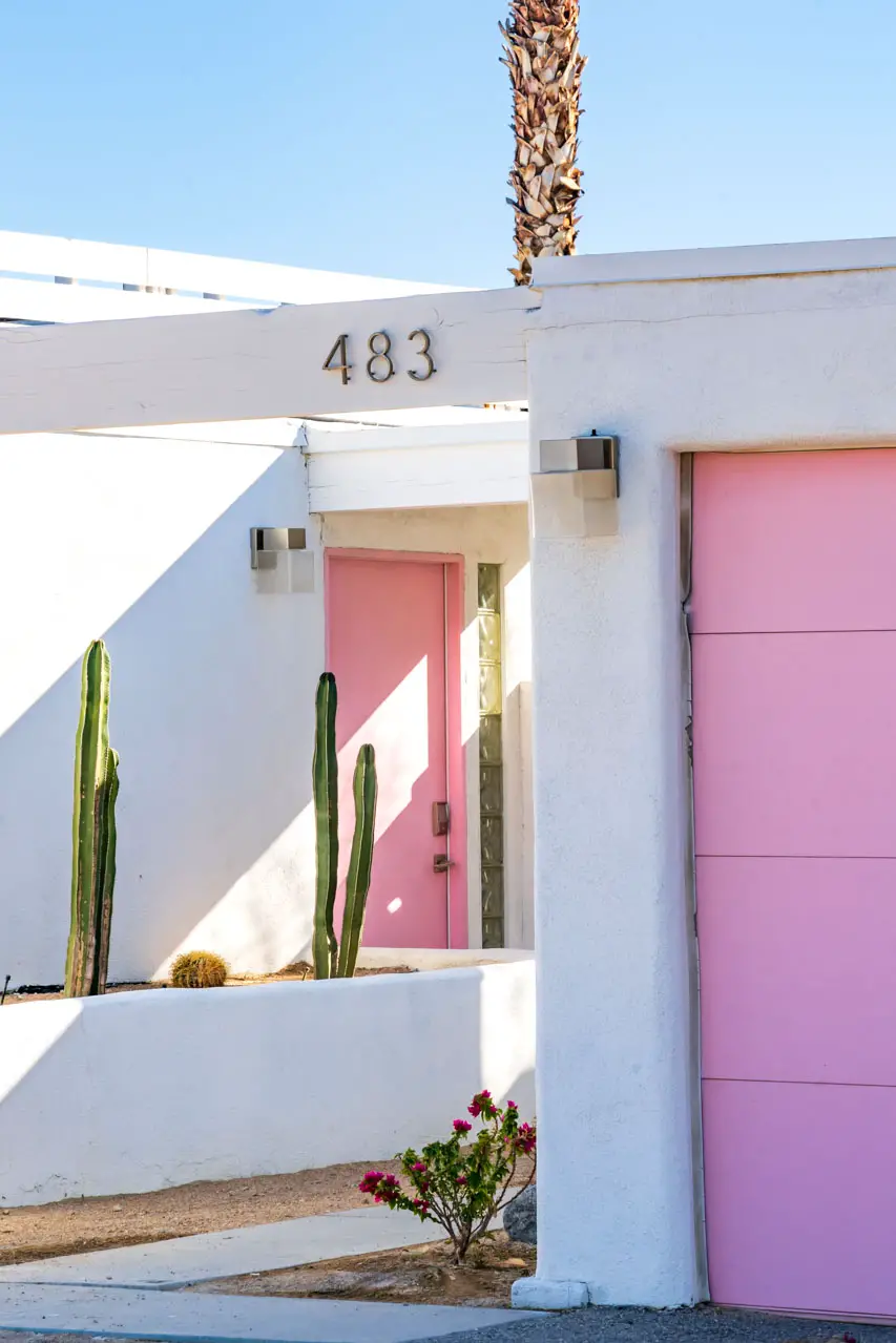 White home with flat roof, pink front door and garage door