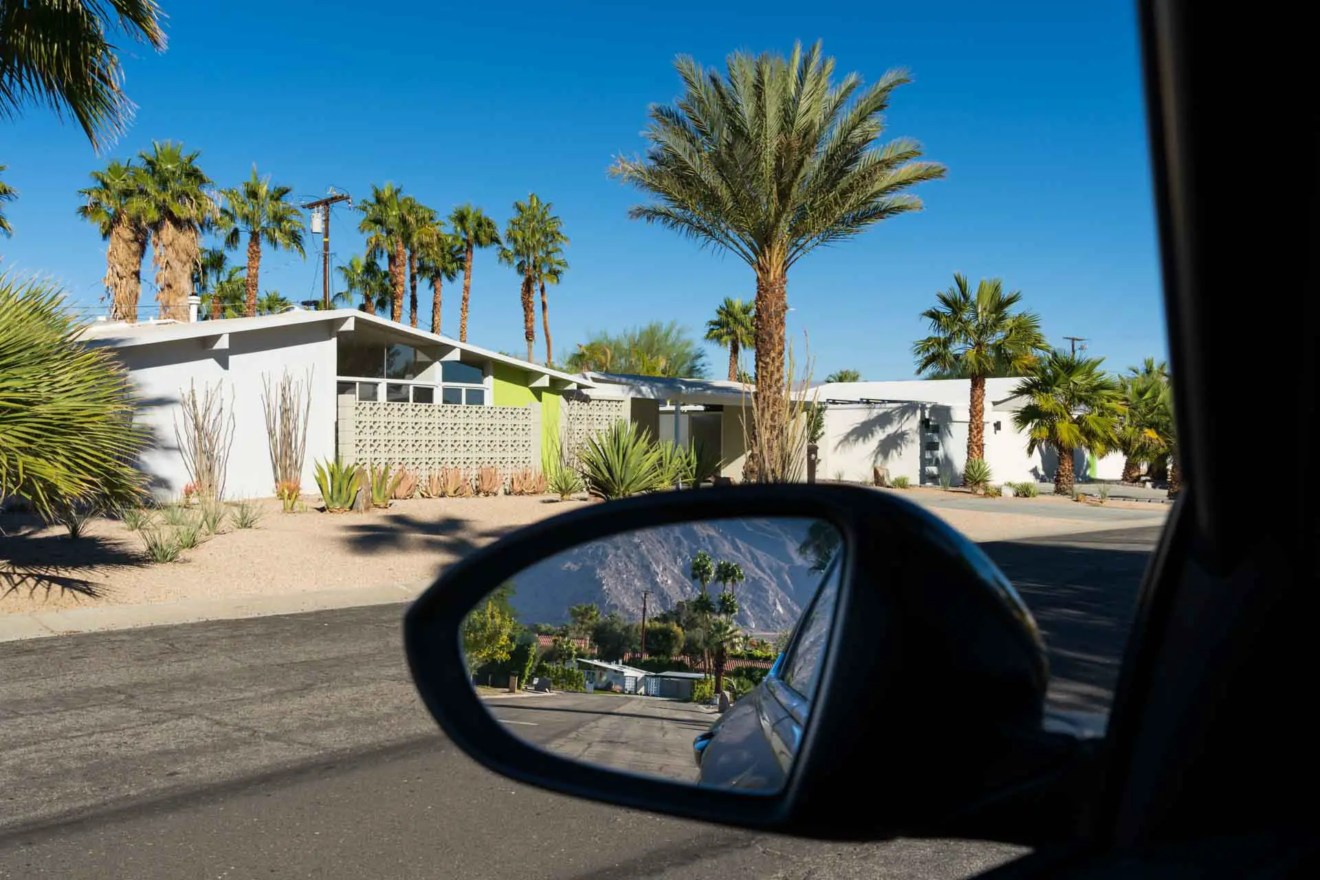 Mid-Century home reflected in rear-view mirror of car