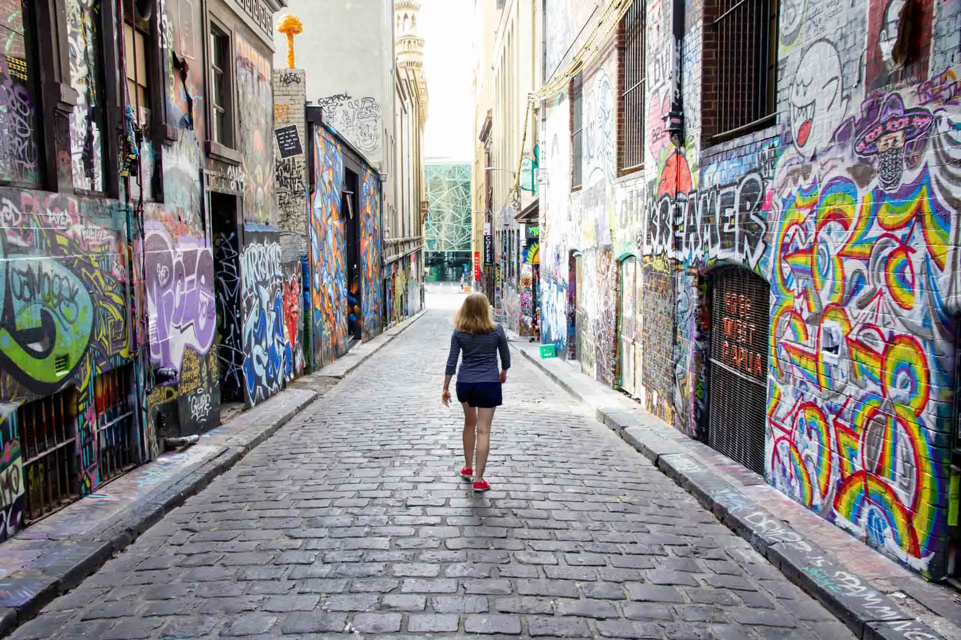 Woman walking down a laneway of Melbourne street art