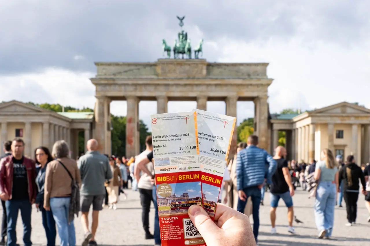 Photo of hand holding Berlin WelcomeCard infront of Brandenburg Gate