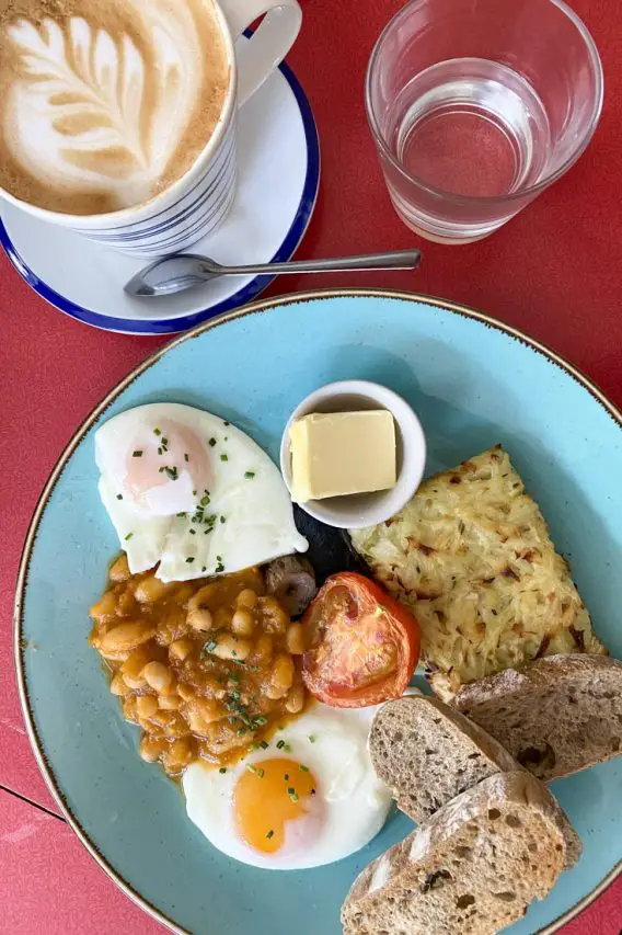 Scottish breakfast and latte on blue plate and red tabletop