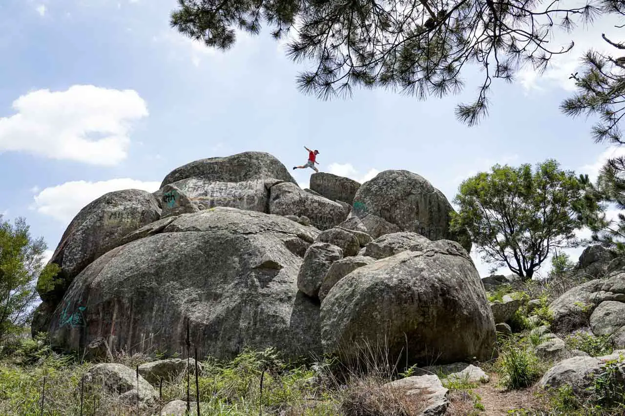 Man leaping on top of pile of granite boulders