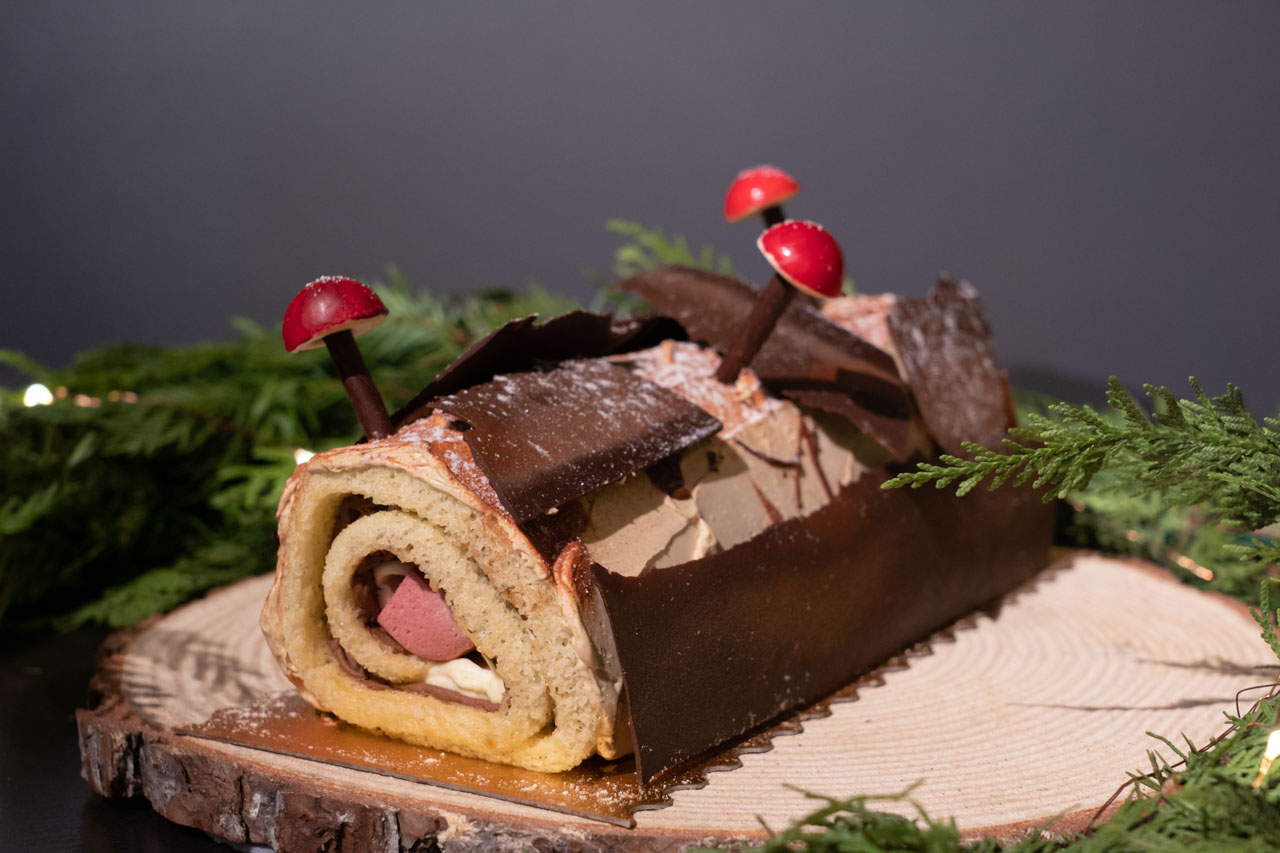 Buche de Noël presented on a birch cutting with evergreen garland