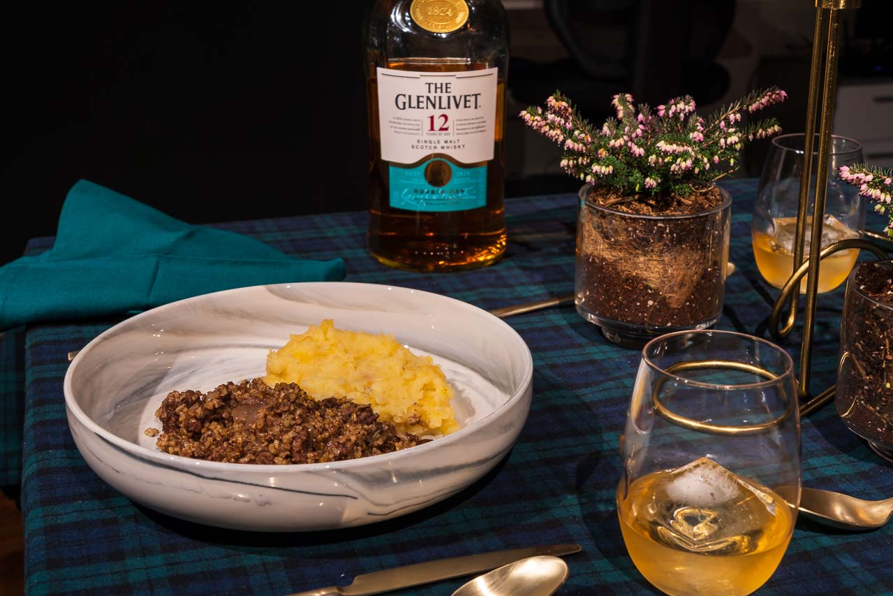 Plate of haggis, neeps and tatties on a Blackwatch tartan tablecloth.