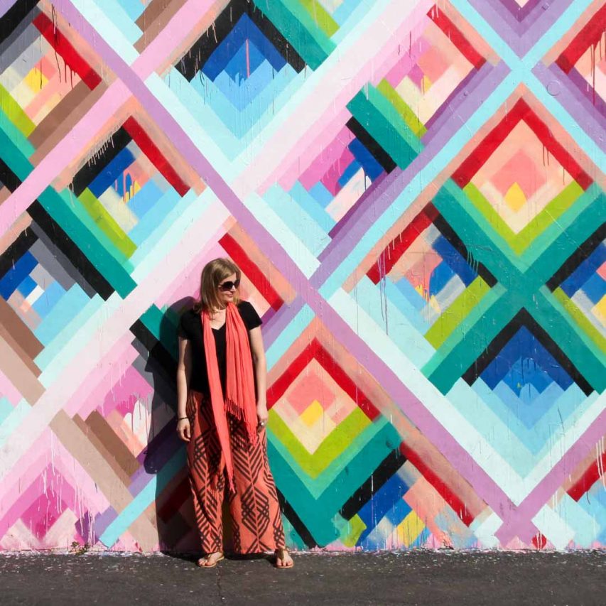 Photo of Madam ZoZo standing against Maya Hayuk mural in Wynwood, Miami