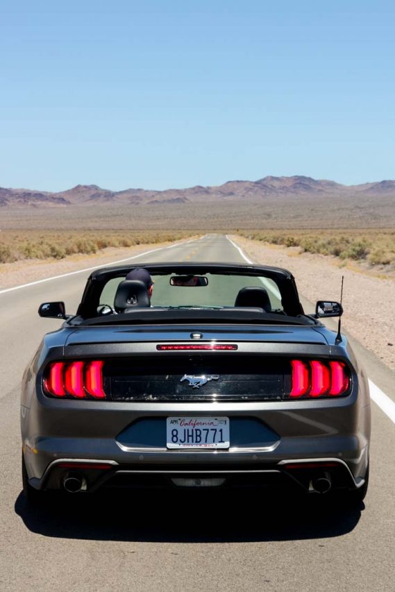 Mustang convertible with top down on a long desert road