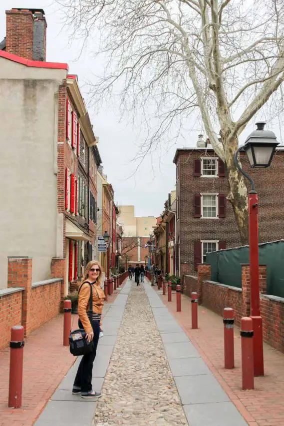 Woman standing in old, cobblestone residential street