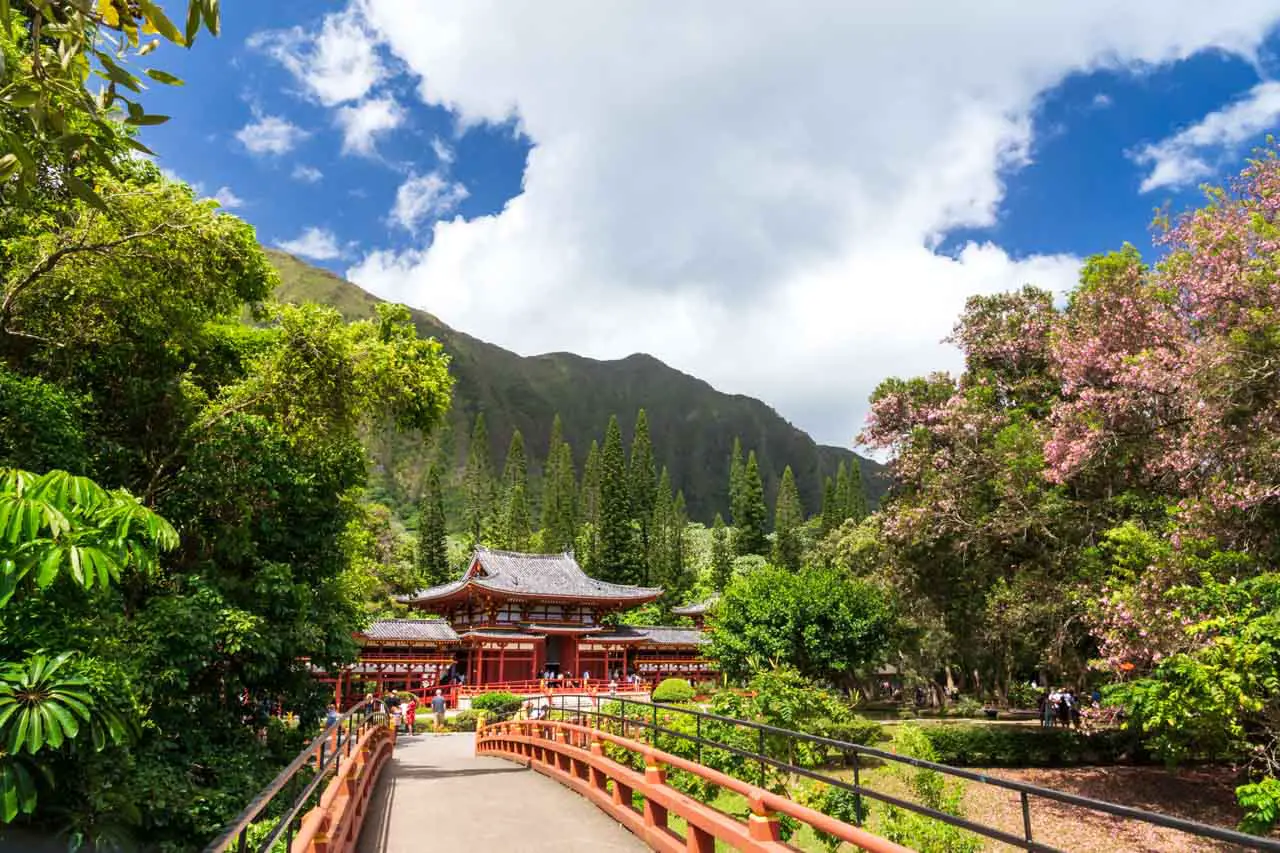 Redd temple backed by green mountains and framed by red bridge