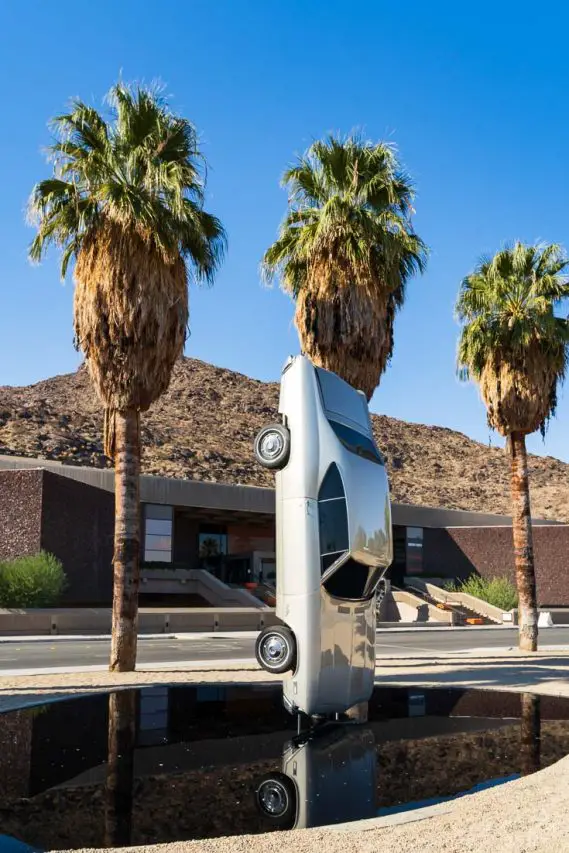 Car suspended vertically over a mirror pool