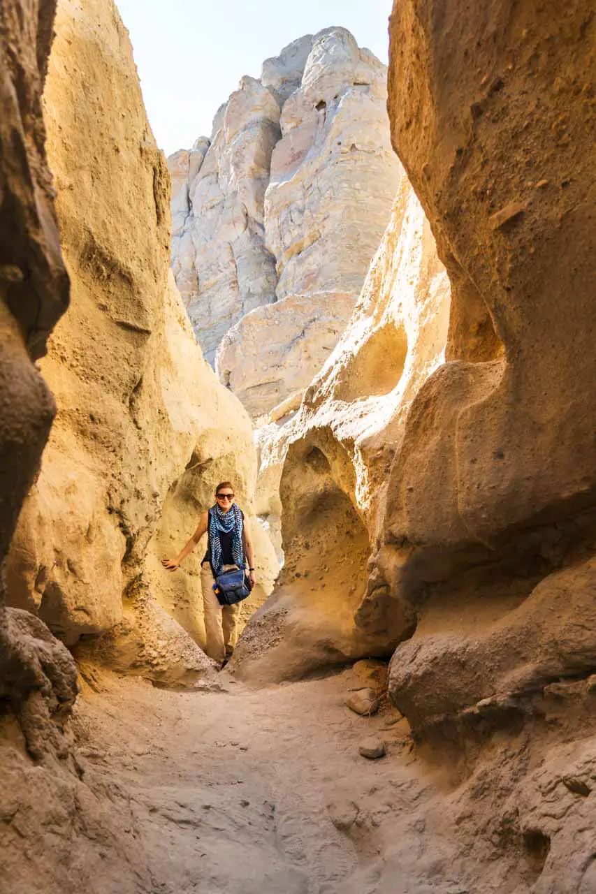 Woman standing in slot canyon with sunlight behind