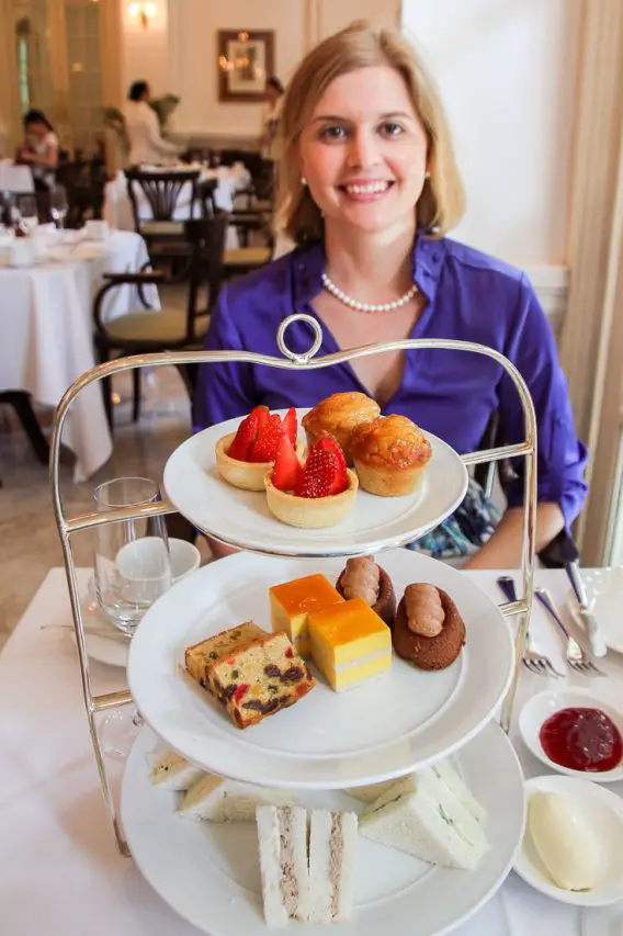 Woman in blue with three-tier stand of afternoon tea