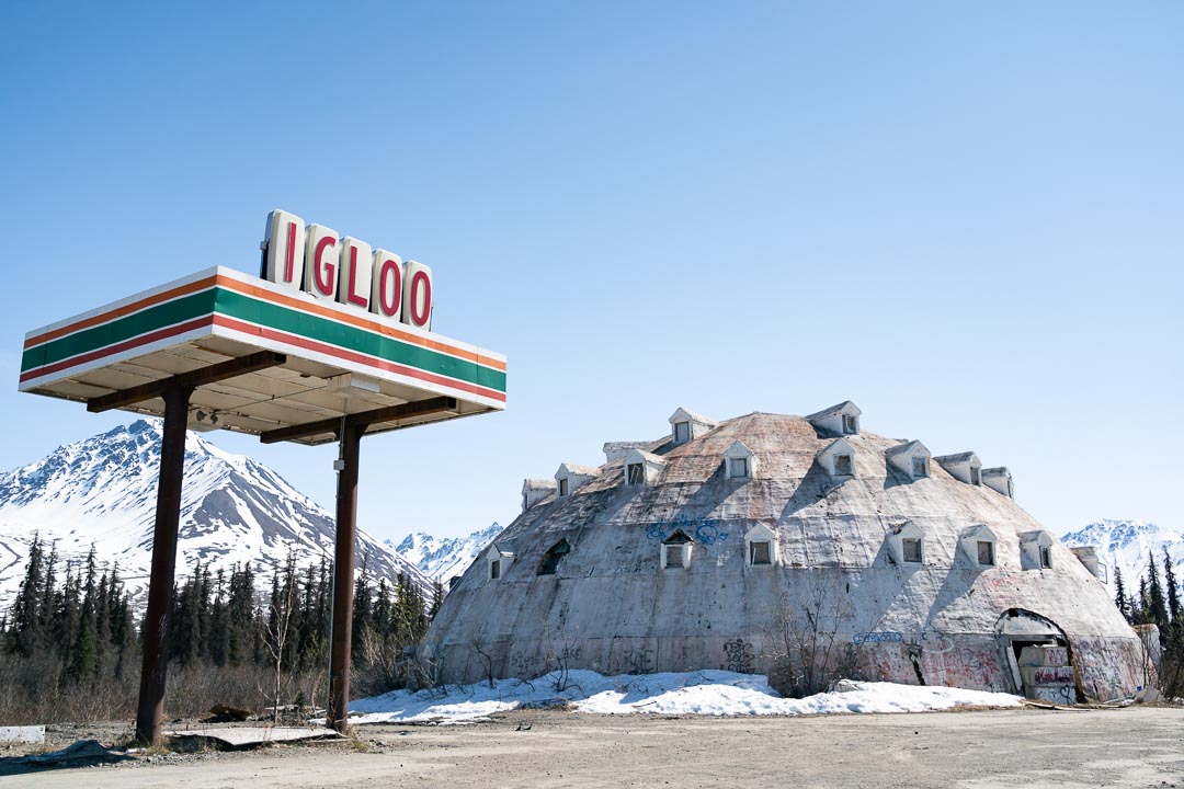 Large, derelict, igloo shaped building with gas station-style shelter baring "Igloo" sign