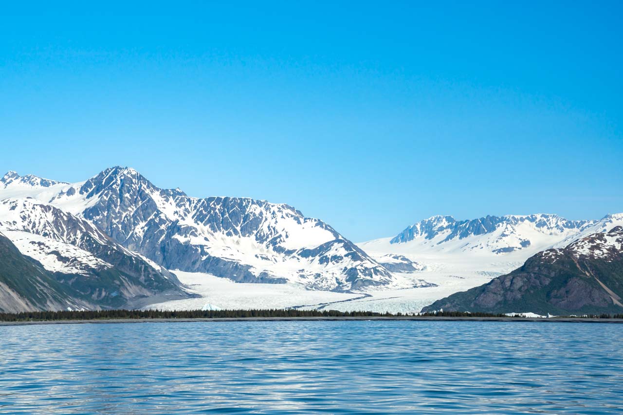 View across water of large glacier descending out of mountains