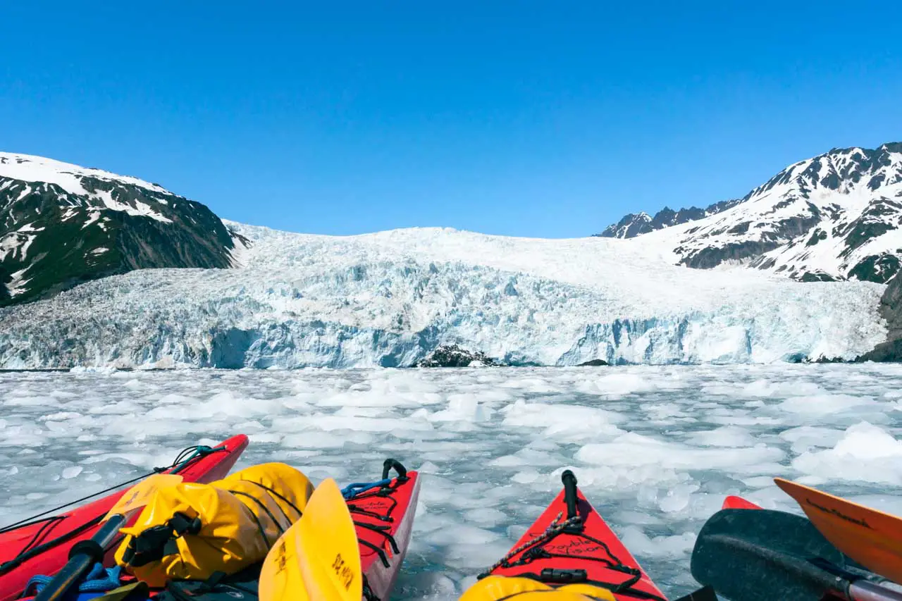 Red kayaks rafted together infront of  Aialik Glacier for an overwater picnic lunch with a view