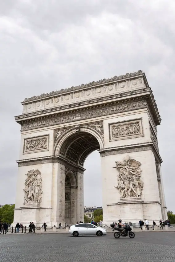 Arc de Triomphe with cloudy sky in background, and traffic in foreground