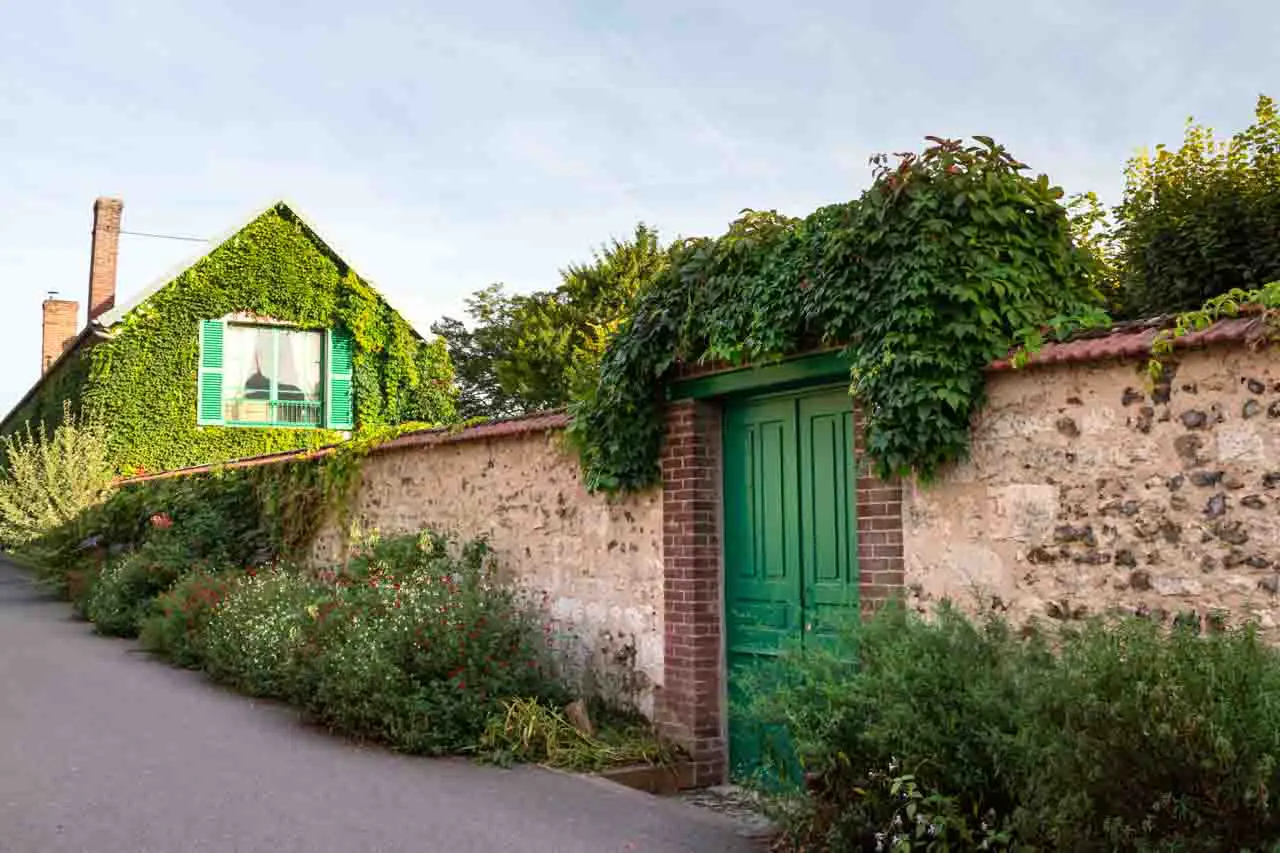 Exterior of walled garden and home with green door and shutters