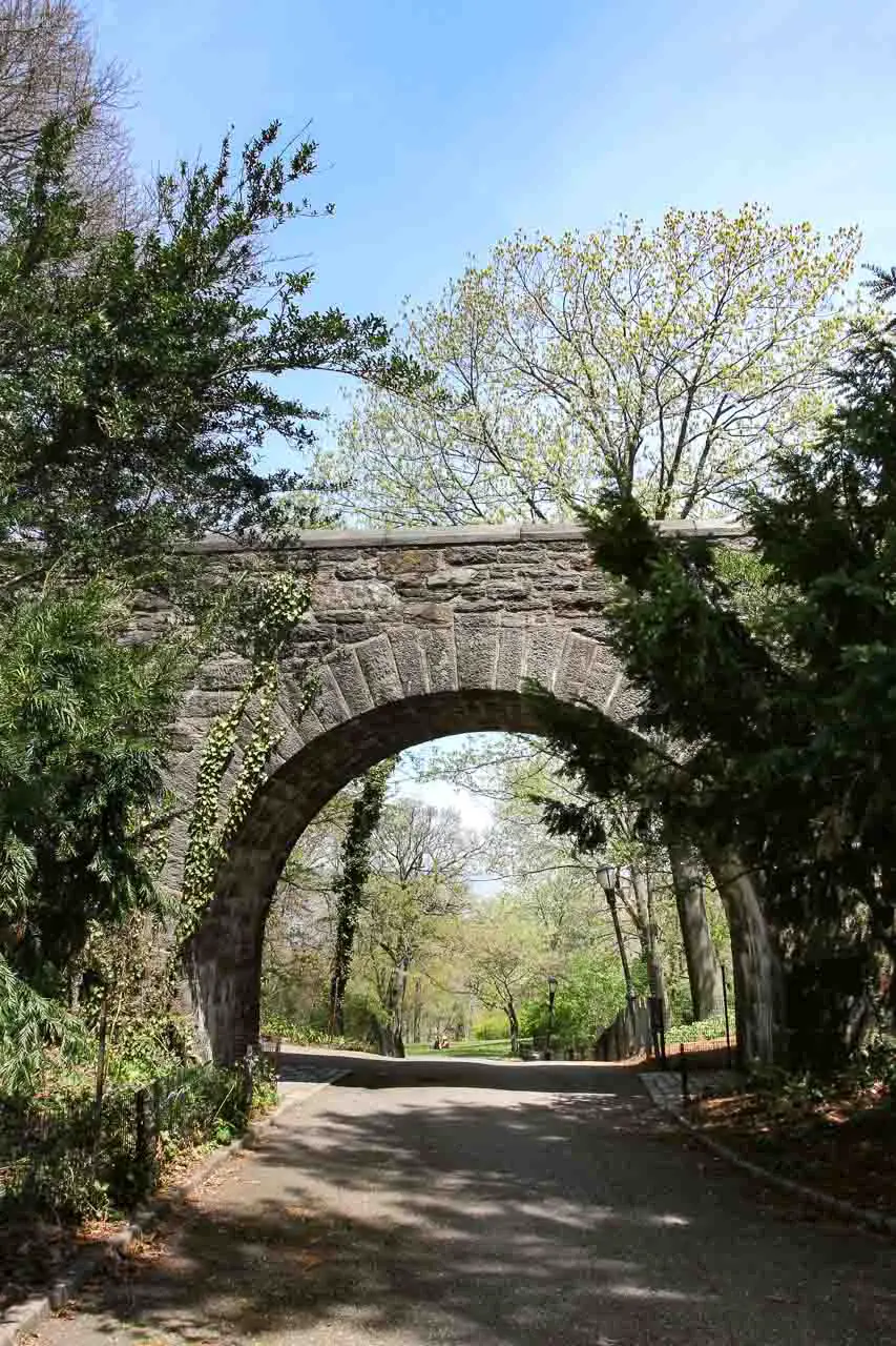 View of parkland through archway of stone bridge