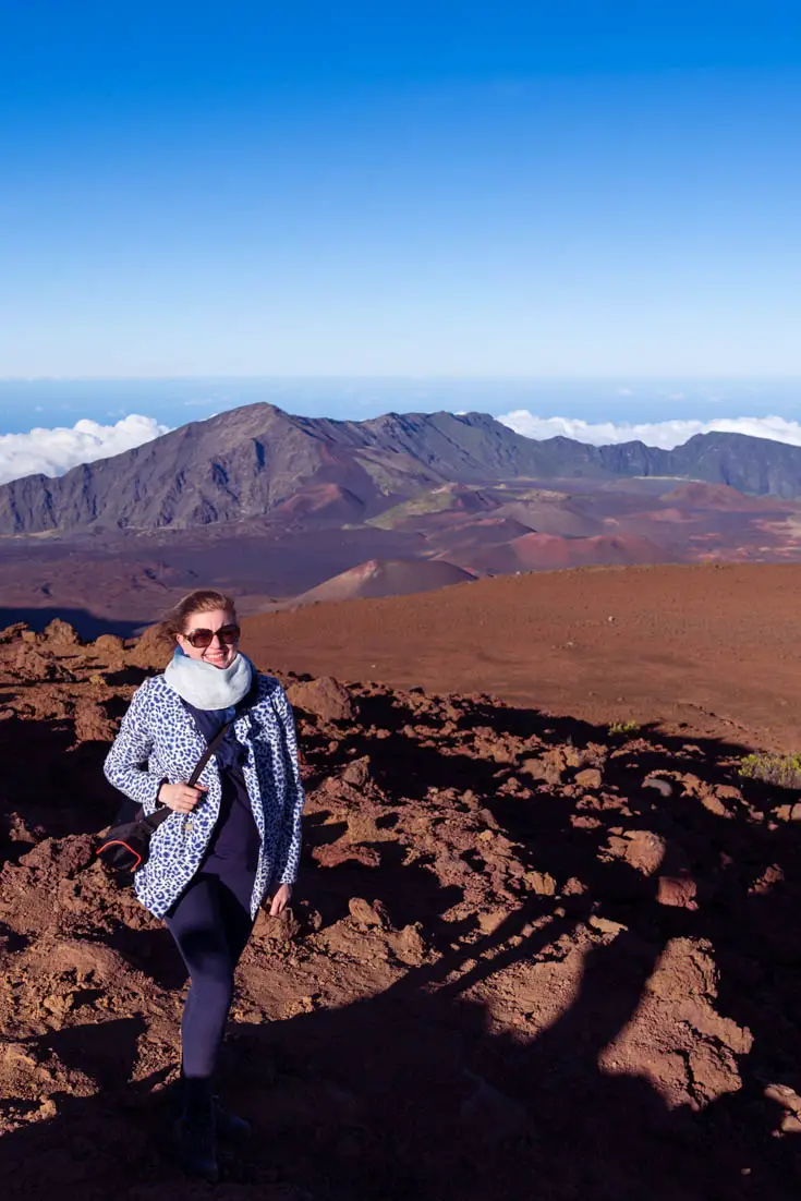 Woman standing on top volcano with blue sky and ocean in the background