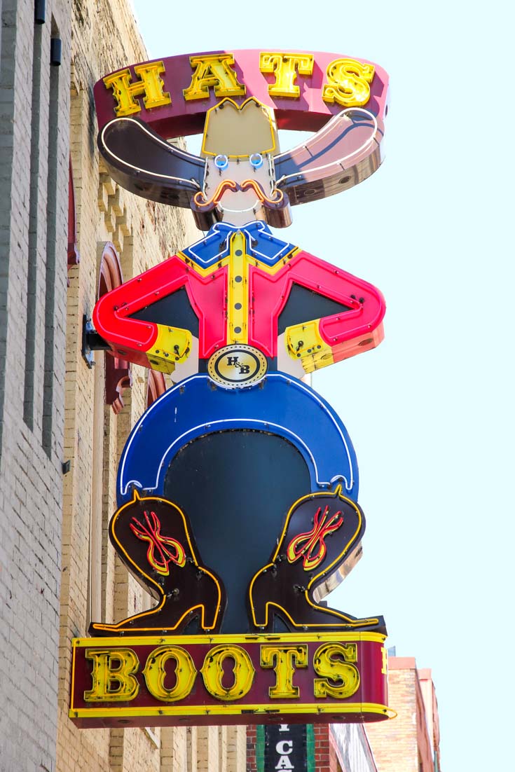 Neon sign in Nashville with bow-legged cowboy advertising hats and boots
