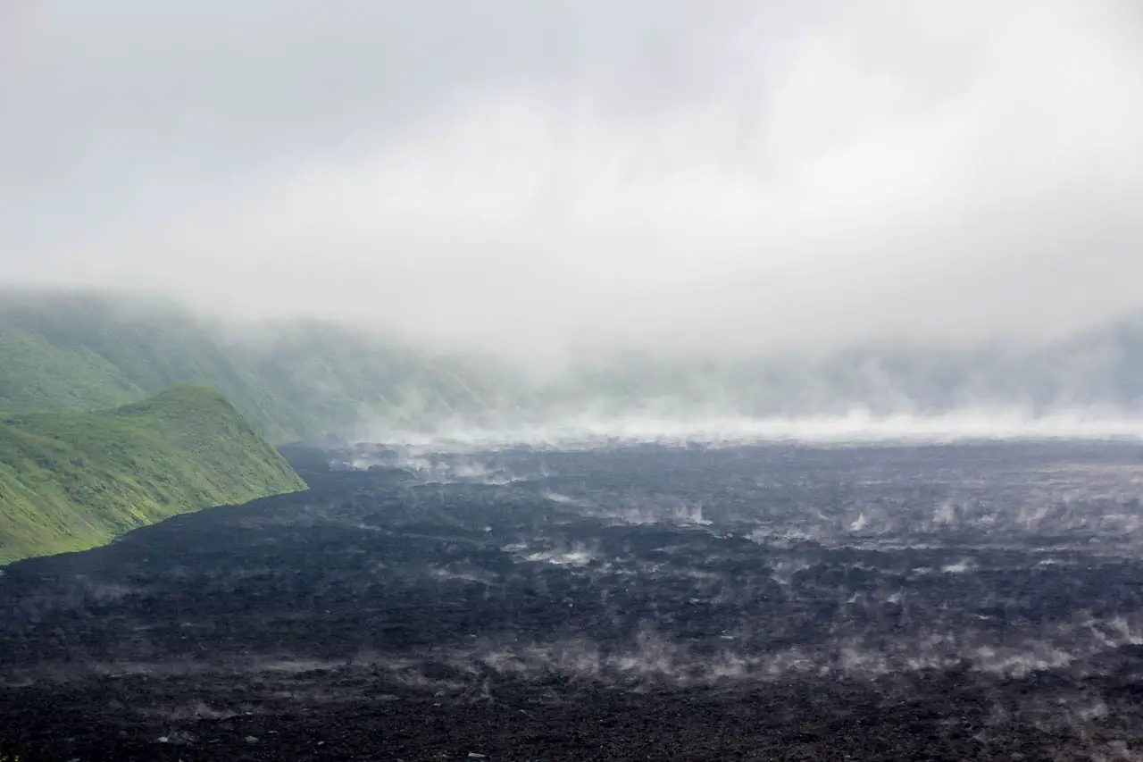 Low clouds meet rising steam in volcanic crater