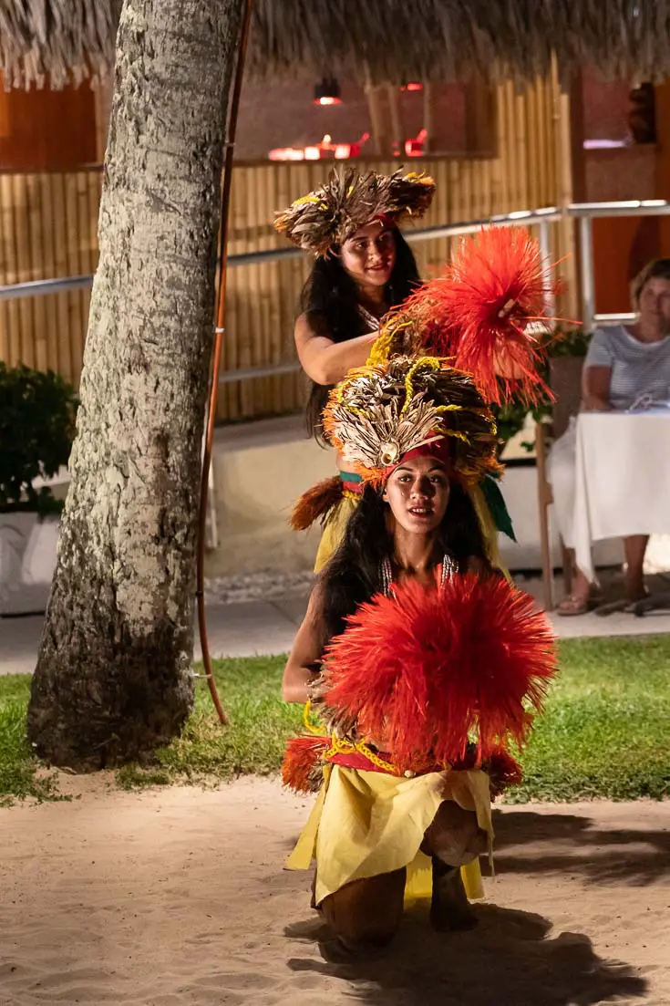 Two female Polynesian dancers performing in yellow and orange traditional dress
