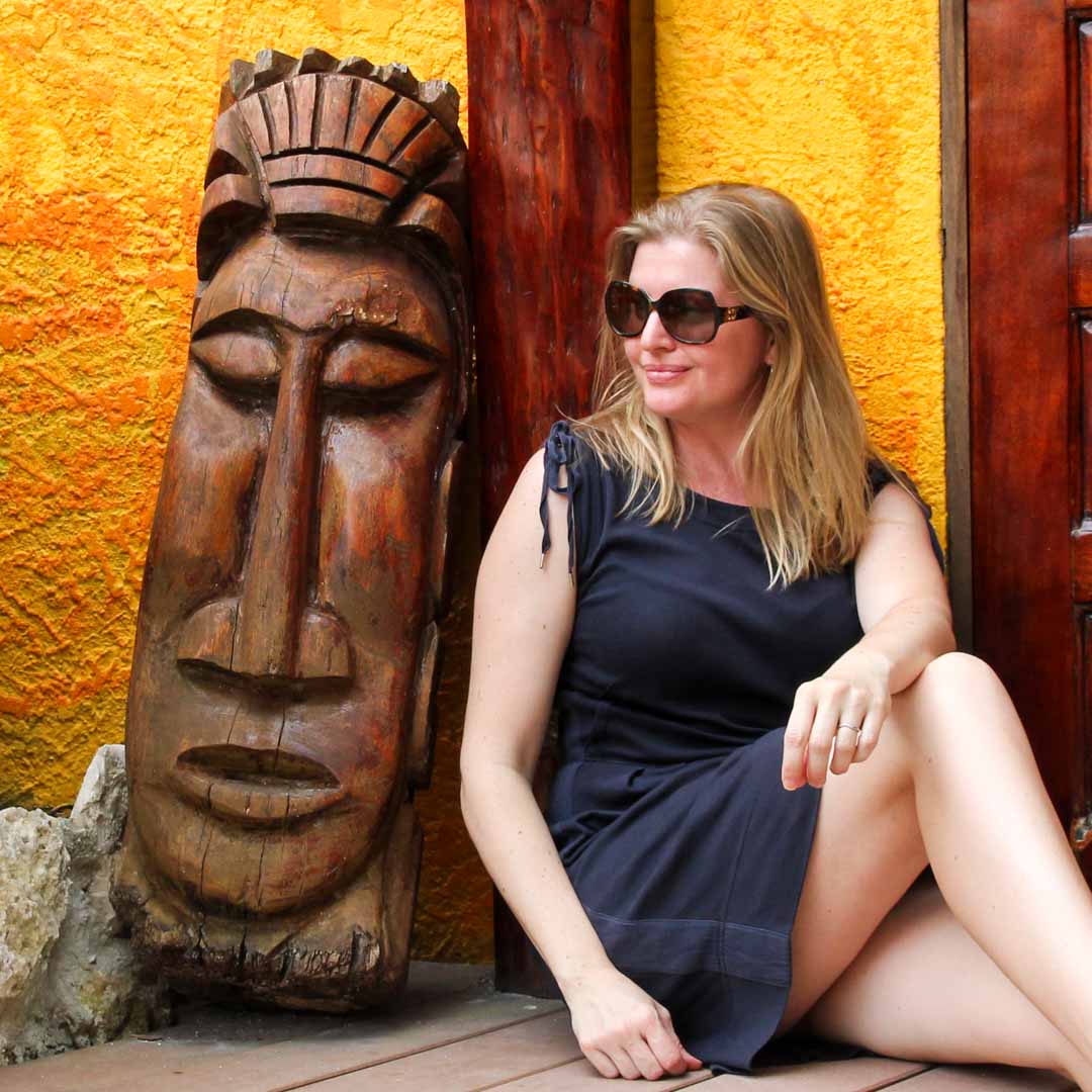 Madam ZoZo in Belize, sitting next to wooden carving of face